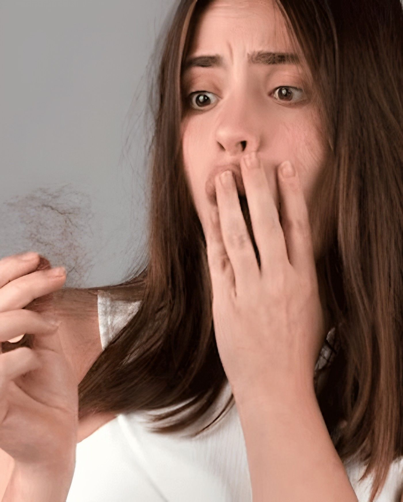 Woman concerned about hair fall, holding shed strands